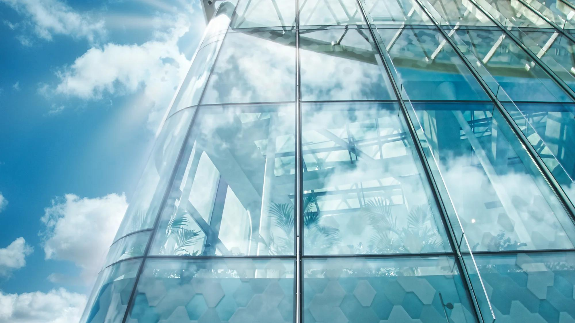 Modern glass office building reflecting sky and clouds